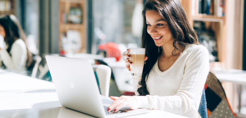 Smiling woman on a laptop with a coffee